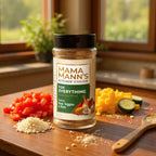Mama Mann's Kitchen seasoning blend jar on a wooden cutting board with chopped vegetables.